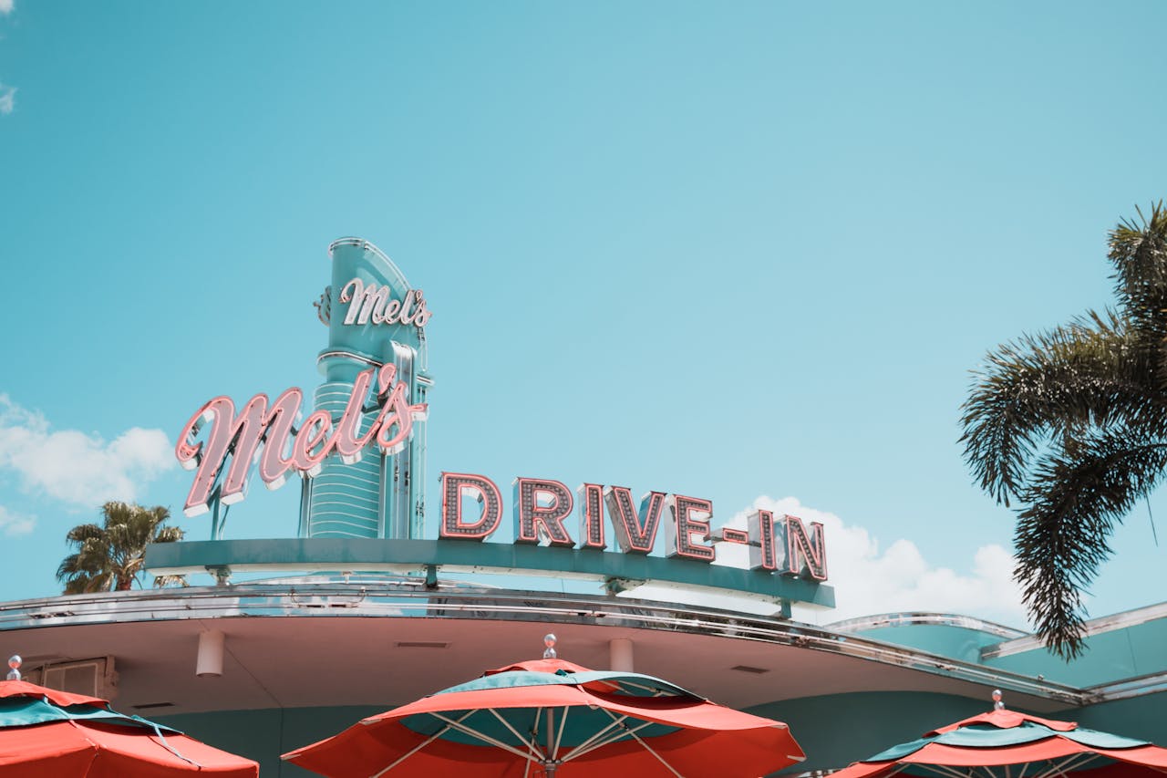 services-01 A vintage drive-in diner featuring classic neon signage and vibrant red umbrellas.